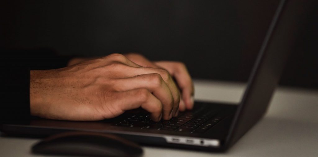 Image of person typing on black laptop