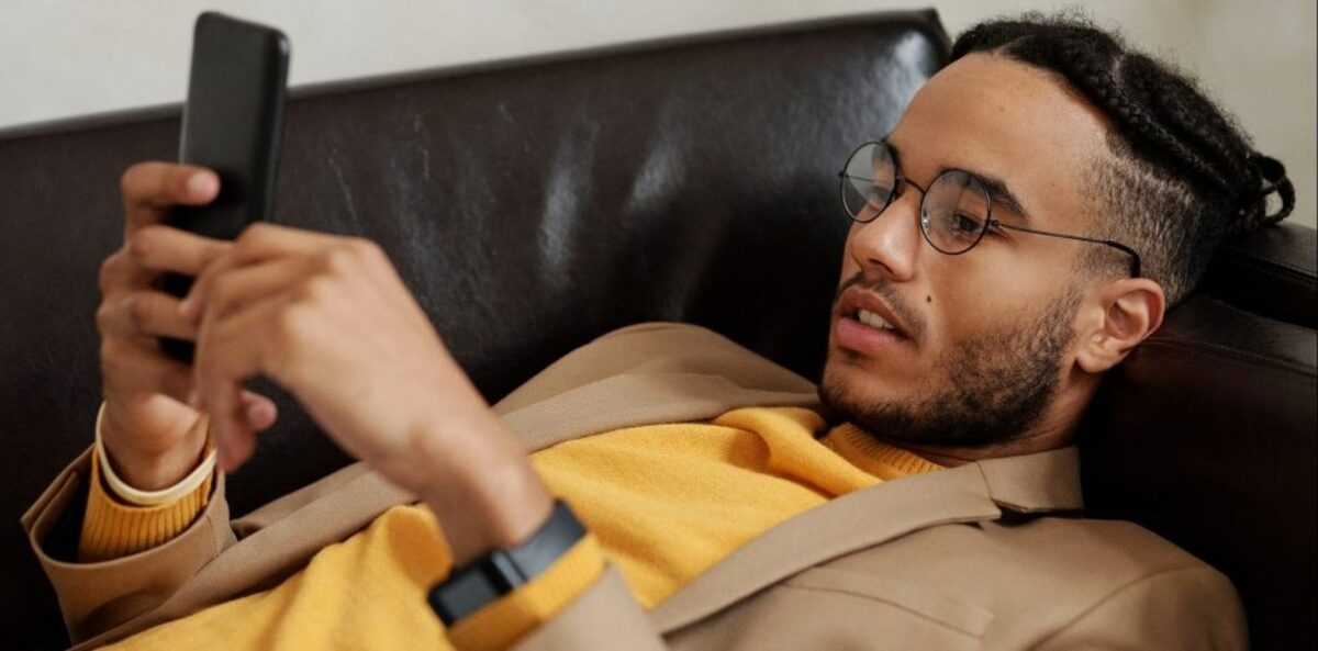 Man in brown coat lying on black leather couch