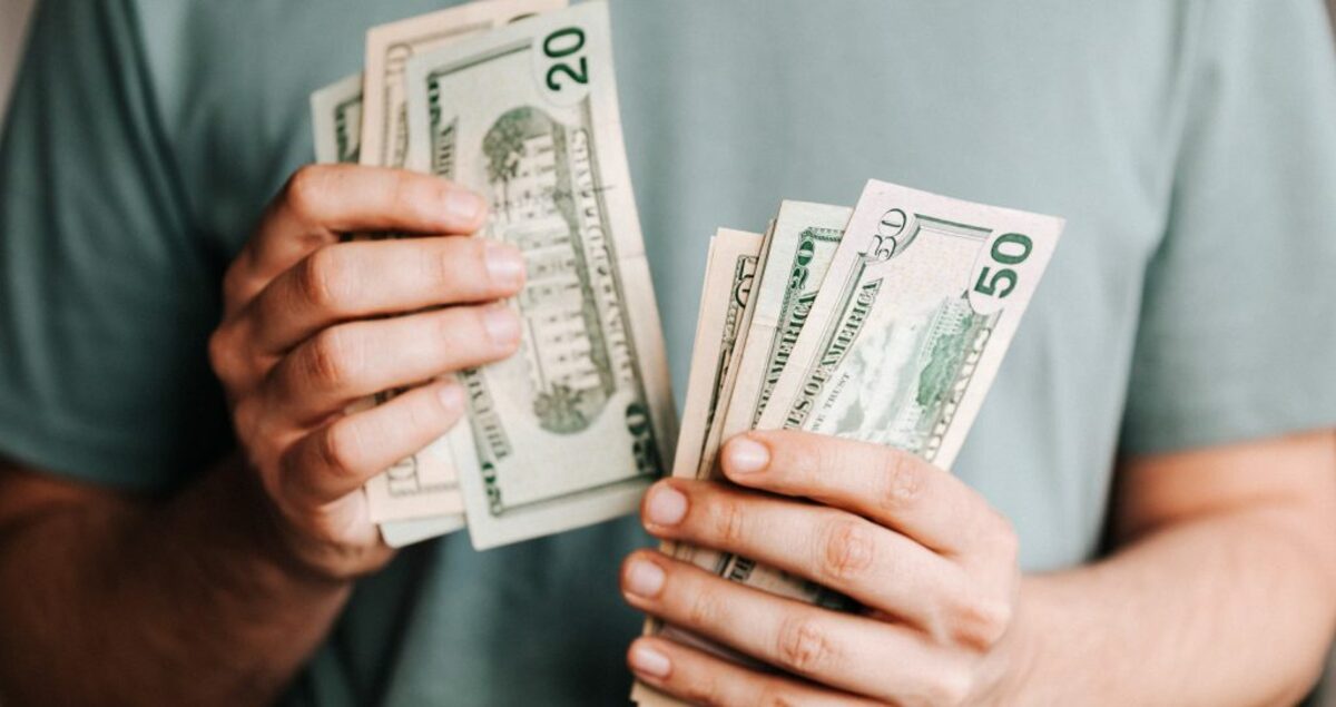 Crop man counting dollar banknotes