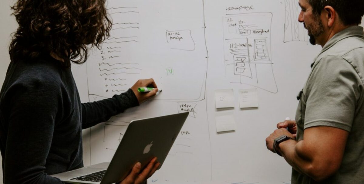 man wearing gray polo shirt beside dry-erase board