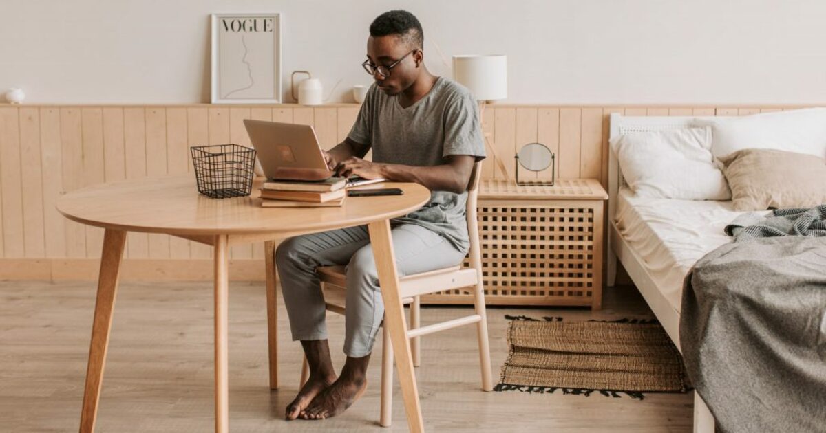 Man in gray crew neck t shirt and blue denim jeans sitting on white couch using