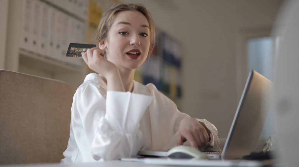 Young woman with credit card paying online