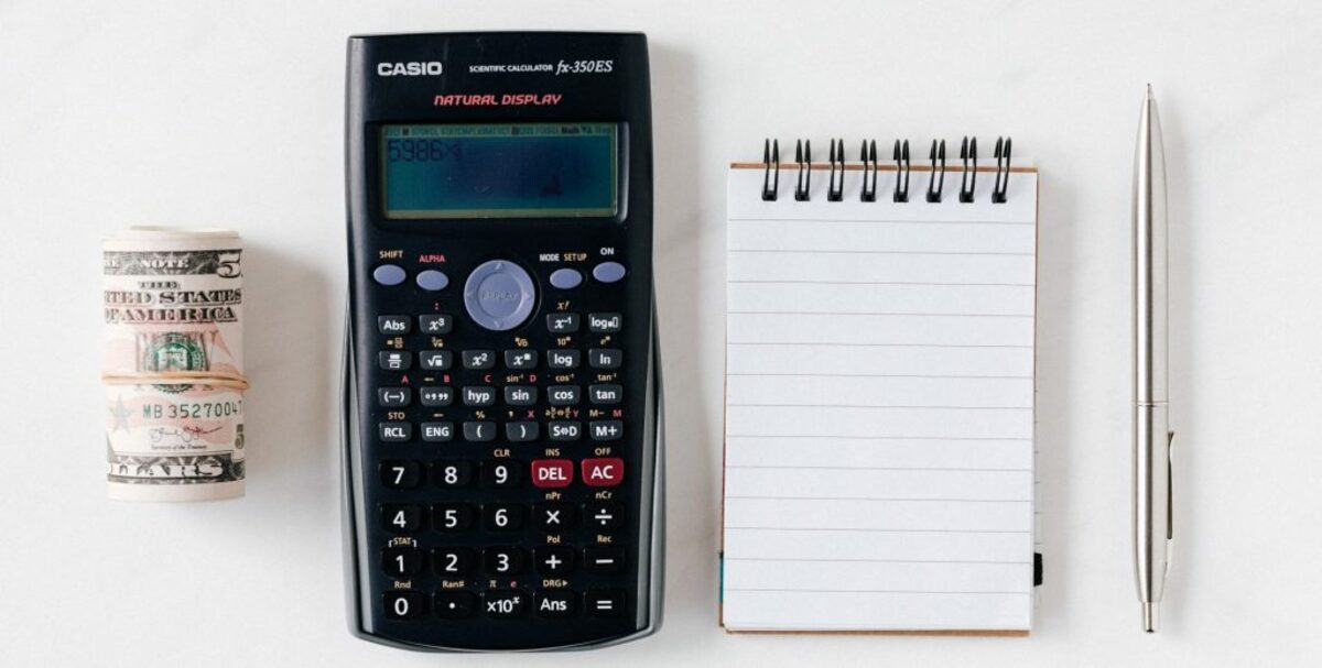 Composition of calculator with paper money and notebook with pen