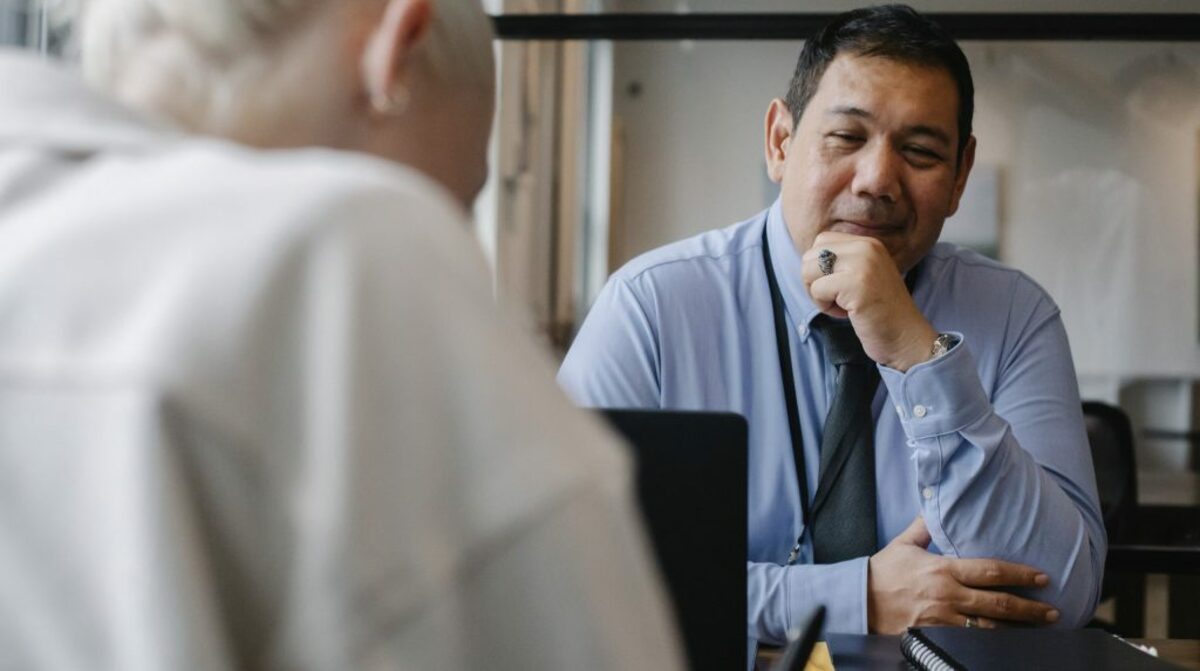 Positive ethnic manager looking at client sitting in office