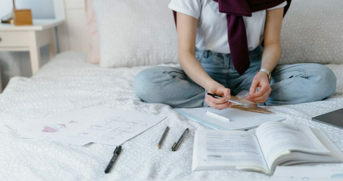 Person in white shirt and blue denim jeans sitting on white bed