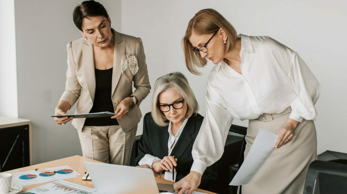 Woman in white blazer holding pen and paper