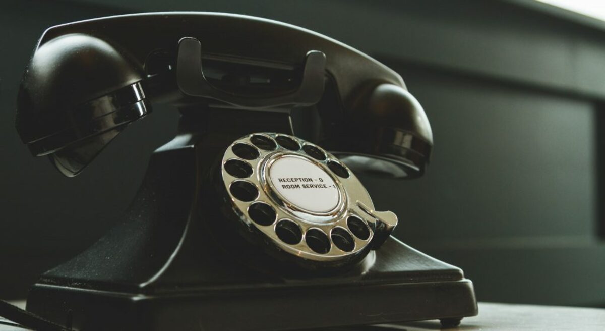 Black rotary telephone on white surface