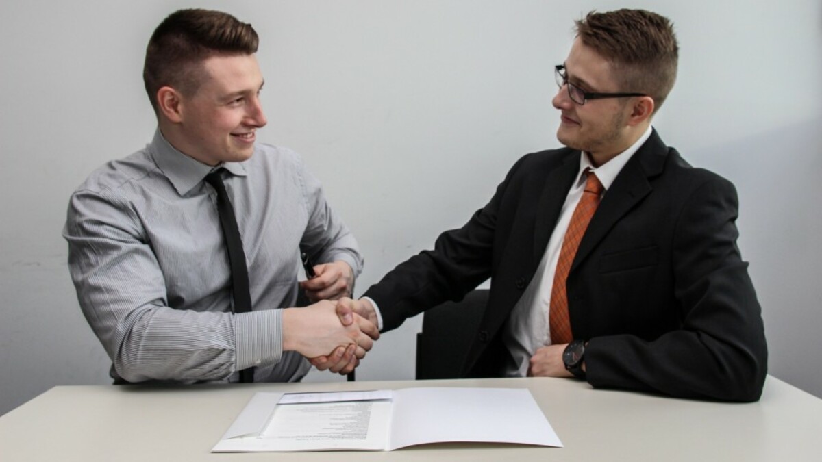 two men facing each other while shake hands and smiling