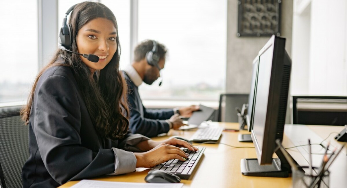 A smiling woman working in a call center while looking at camera