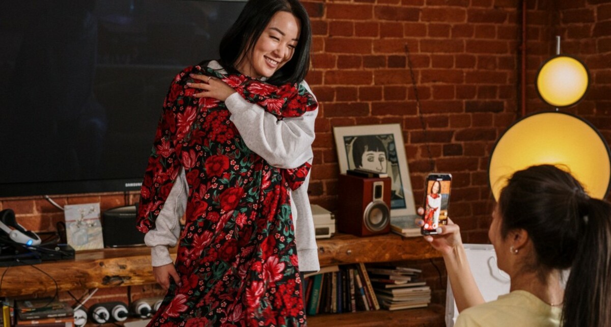 Woman in red and black floral long sleeve dress holding white ceramic mug