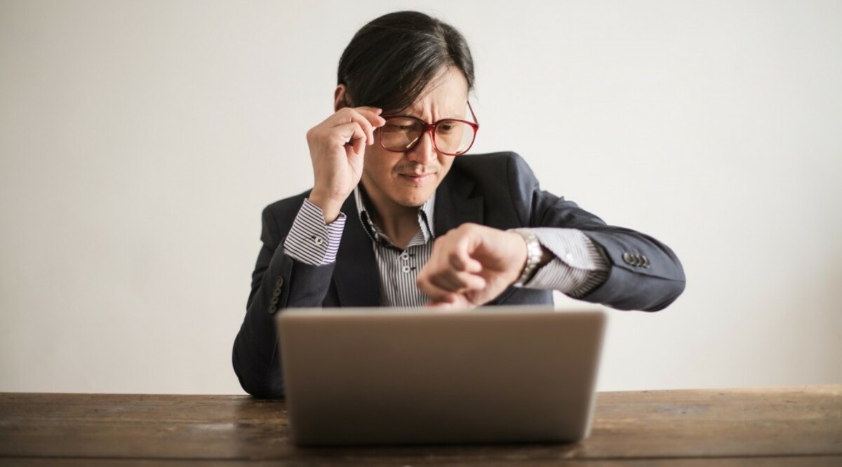 Confused businessman checking time on wristwatch