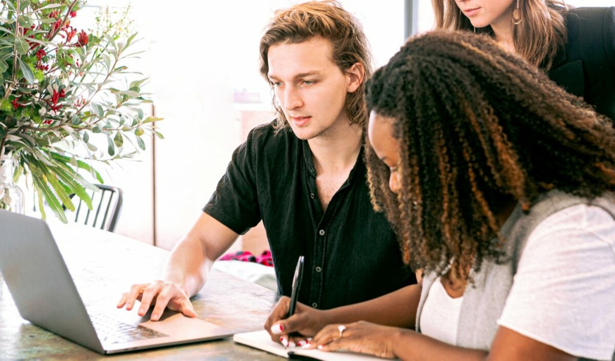 Man working on laptop while woman takes notes