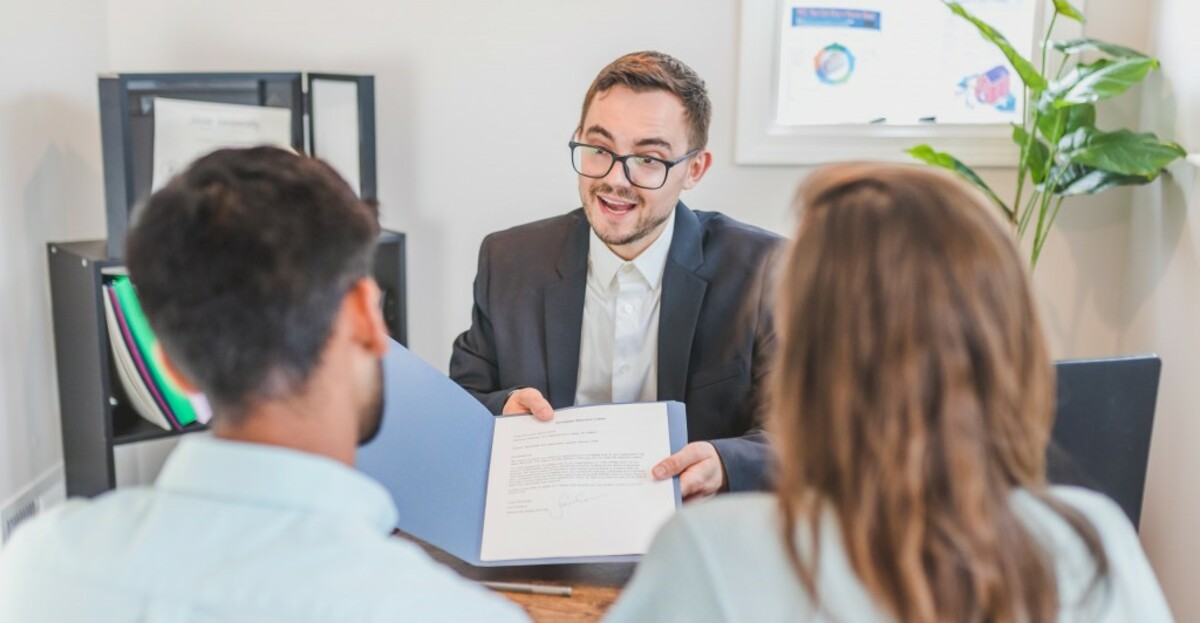 A broker showing a couple the mortgage contract