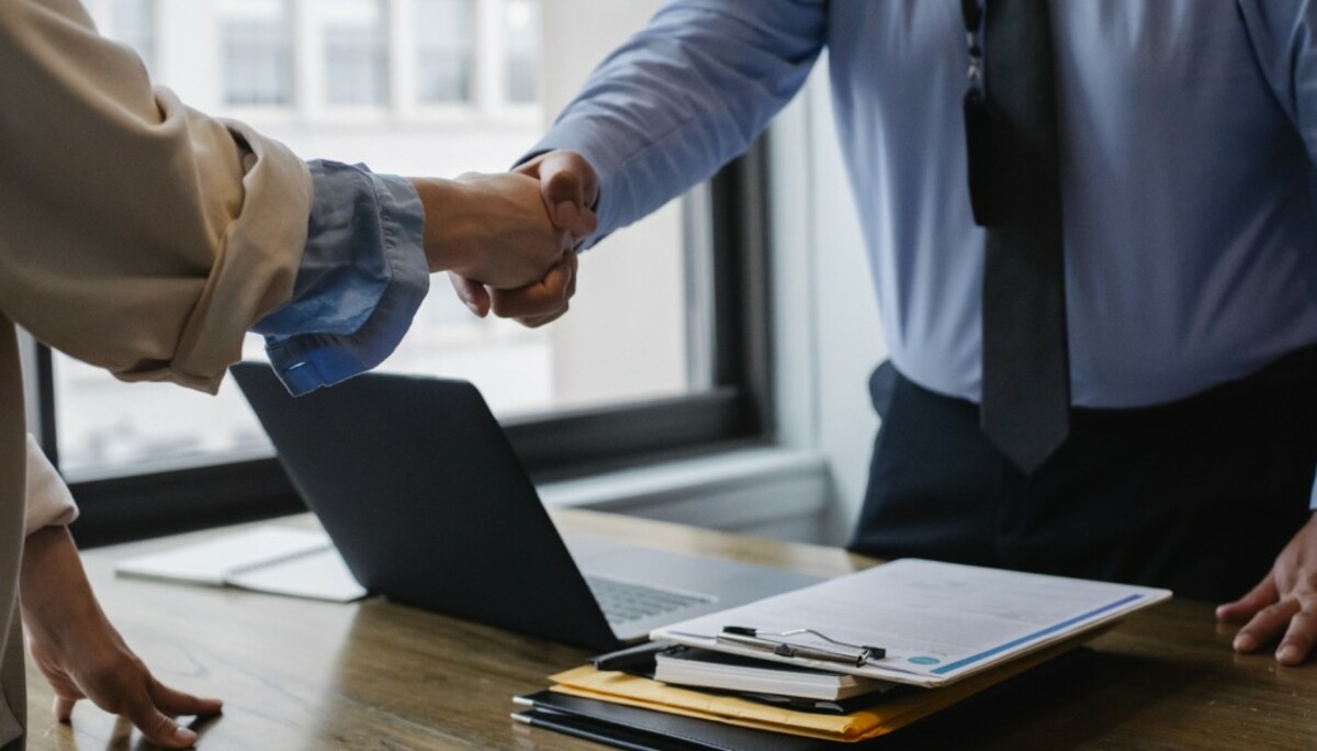 Crop colleagues shaking hands in office