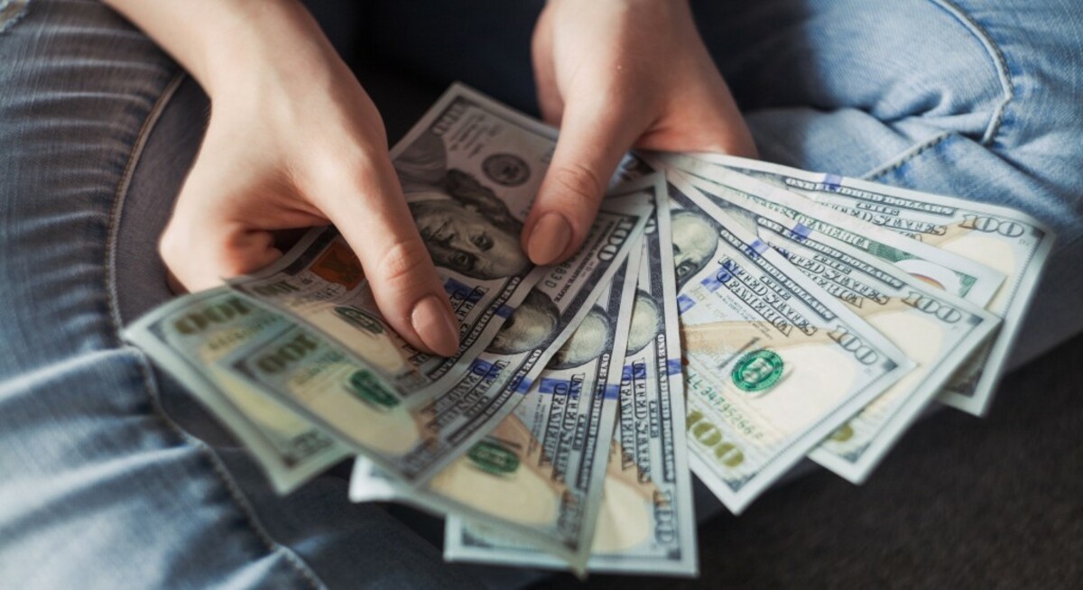 Person holding 100 us dollar banknotes