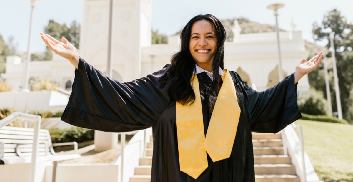 Woman in black and yellow graduation dress smiling