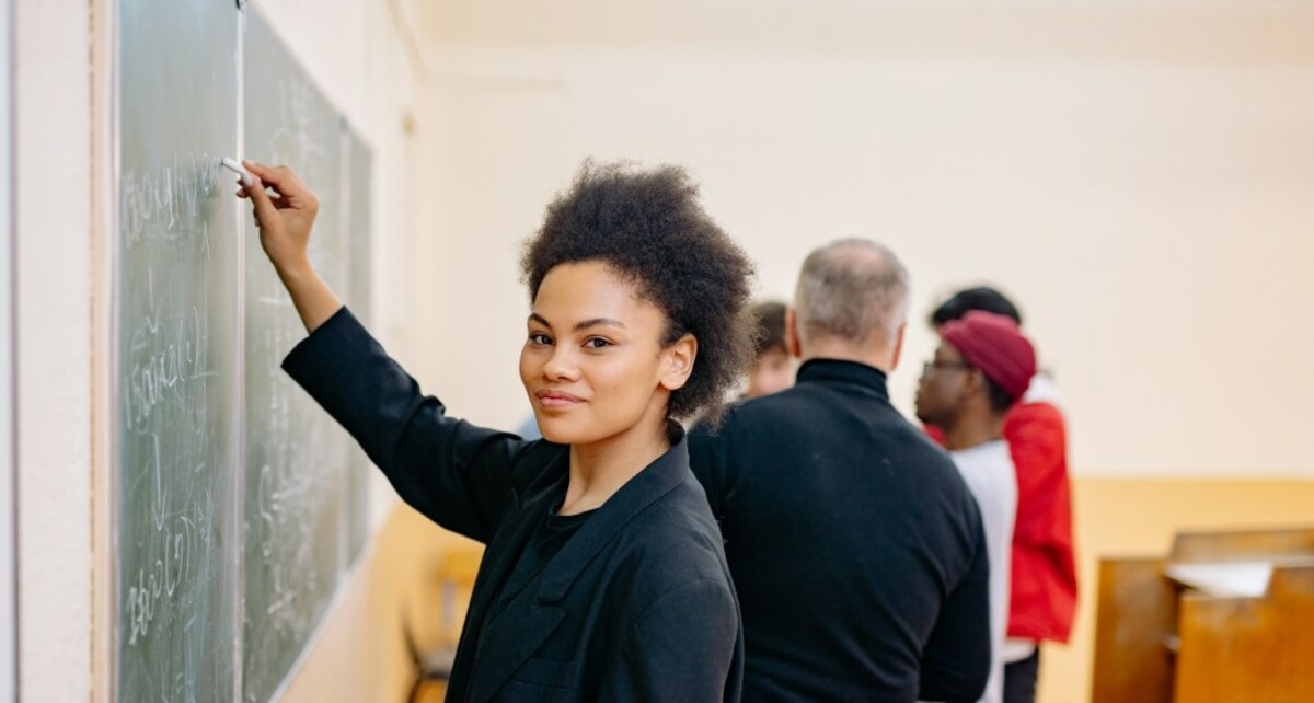 Woman in black blazer wring on a blackboard