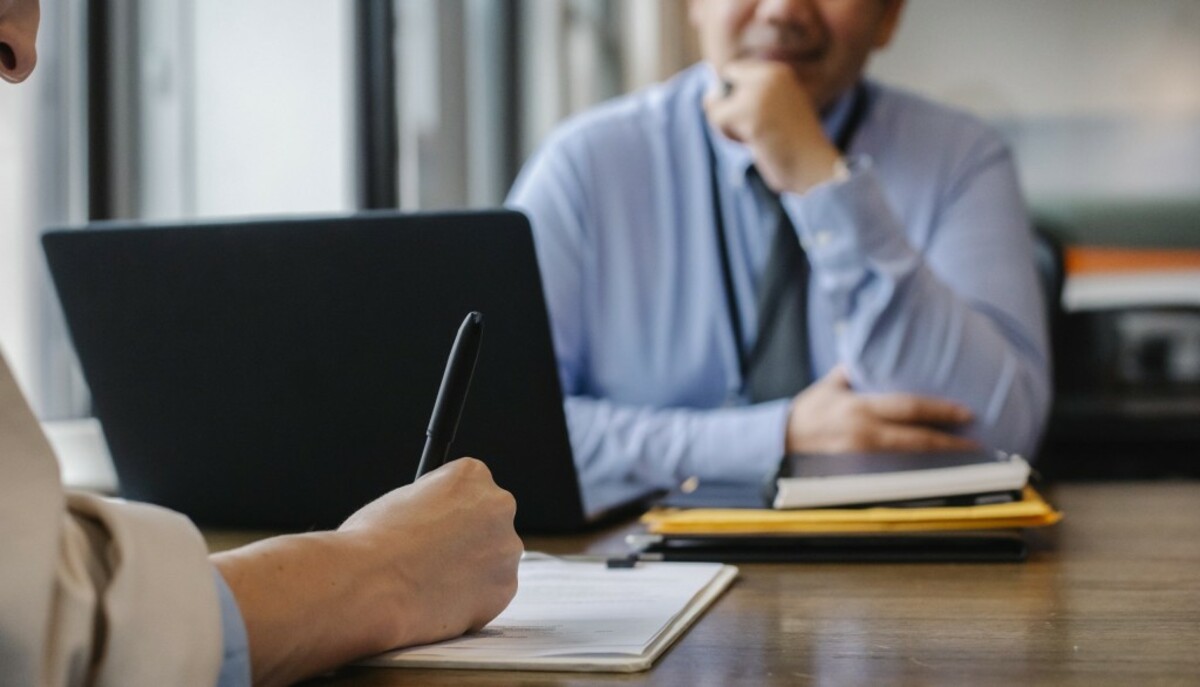 Woman filling job application form in office with boss