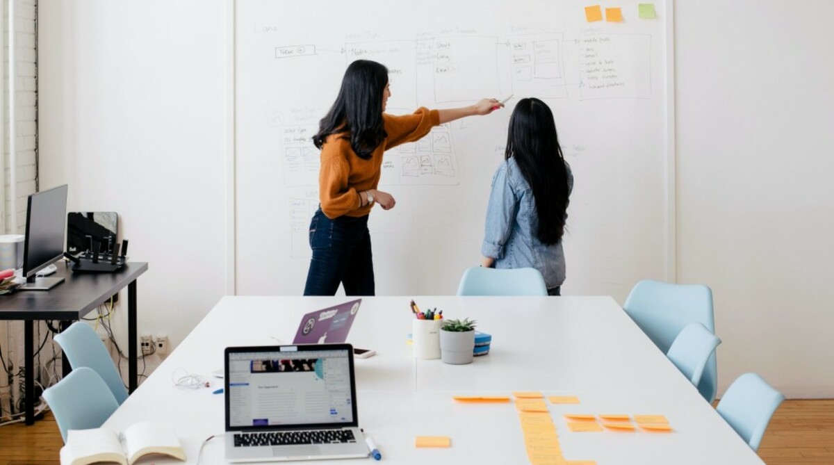 woman in brown long-sleeved shirt in front of dry erase board