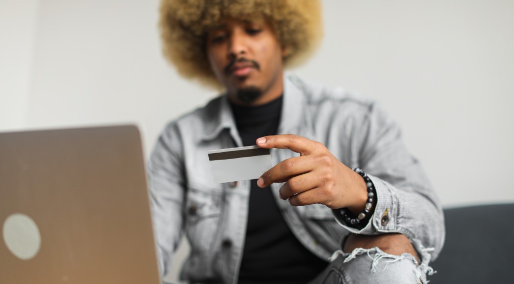 A man with an afro hair holding a credit card