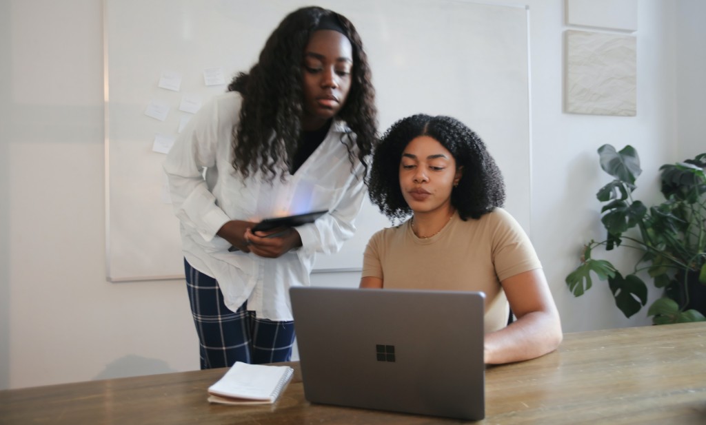 Female colleagues collaborating with a Surface laptop in a board room