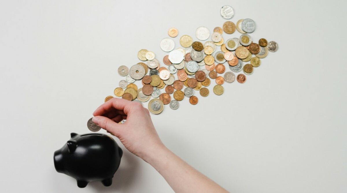 Person putting coin in a piggy bank